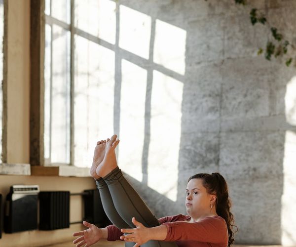 Yoga mat rolled out on a wooden floor next to a window with morning light.